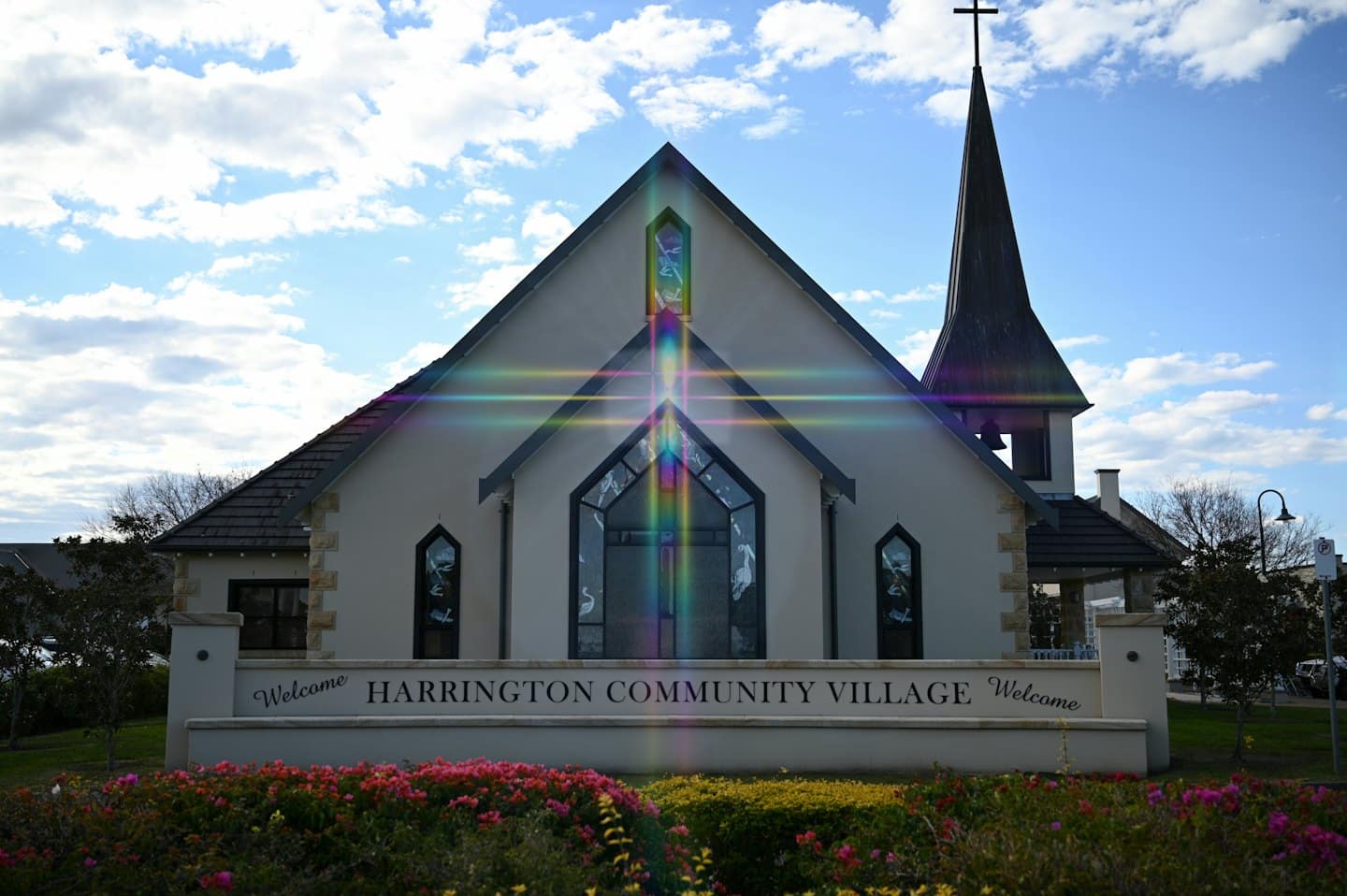 Harrington Community Village church building with a sign and flower beds.